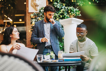 A diverse group of business professionals brainstorming and strategizing in a contemporary coffee bar setting, collaborating on a project with engaging discussion and creativity.