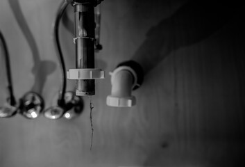 selective focus on a bathroom sink drain disconnected with a hair clog hanging down