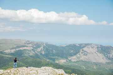 Female taking pictures of forest view from mountain top on hike