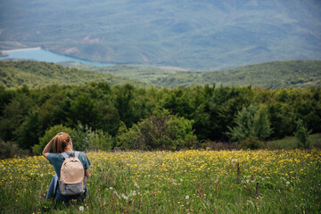 Fototapeta premium Female resting and looking at the forest from the top of the mountain on a hike