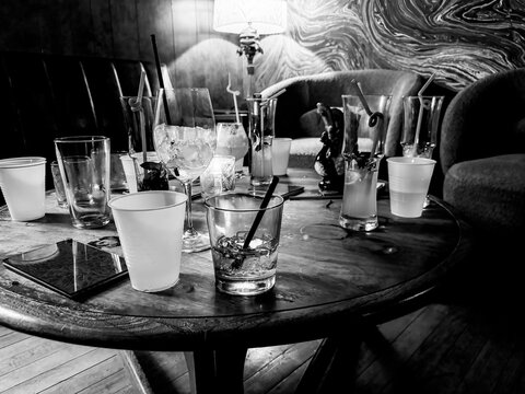 Scattered glasses and empty drinks on a bar table after a party - Powered by Adobe