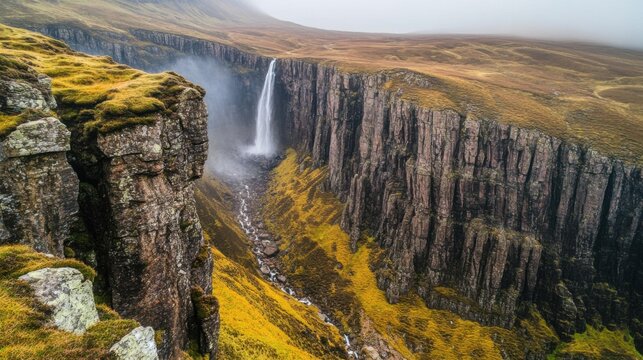 Majestic waterfall cascading into a stunning gorge surrounded by lush greenery and rugged cliffs on a foggy day in a remote and beautiful landscape - Powered by Adobe
