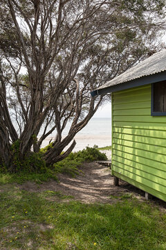 Bright green bathing box surrounded by sand in Blairgowrie, Victoria, Australia