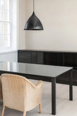 Modern dining area featuring a sleek black table and woven chairs in a bright space