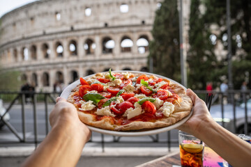 Colosseum (Colosseo) exterior with Margherita pizza in hand . Rome, Italy.