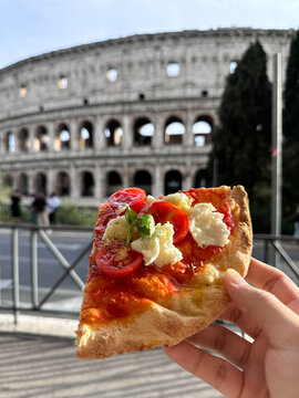 Colosseum (Colosseo) exterior with pizza in hand. Rome, Italy.