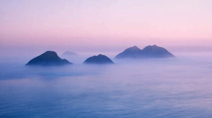 A misty morning scene with distant islands barely visible through the fog, surrounded by calm ocean waters
