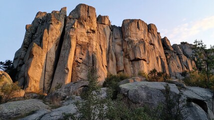 Fototapeta premium Massive rock face at golden hour, sculpted by nature.