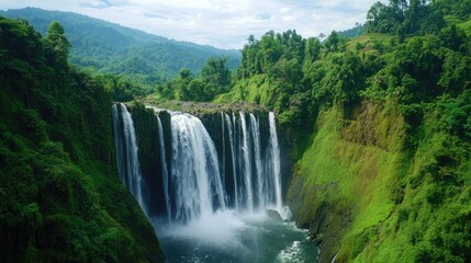 Fototapeta premium A majestic waterfall cascading over moss-covered rocks, surrounded by lush greenery, creating a natural spectacle