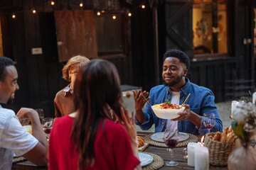 Young, black man enjoying dinner with his friends