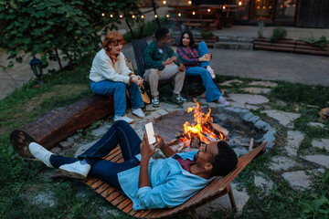 Man scrolling on his phone on a cozy evening by the fire pit