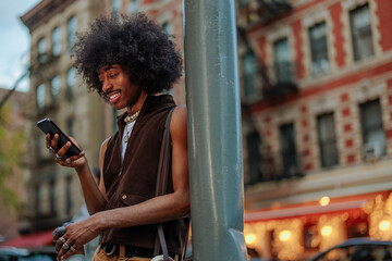Young man smiling using his smart phone in urban city setting