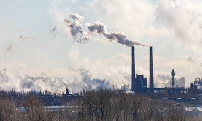 A large industrial plant is spewing smoke into the sky