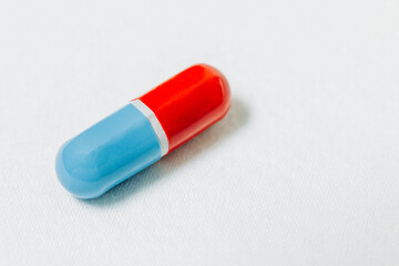 Close up of single red and blue capsule on white background