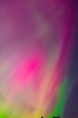 Pink and green aurora borealis against a starry sky