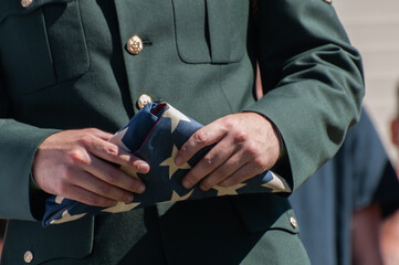 Military officer holding a folded American flag during a ceremon