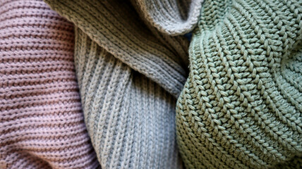 Background is filled with knitted fabric of gray, turquoise, purple colors. Fabrics of different colors are randomly arranged. Fabric has folds. Different texture of knitting