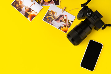 Photo camera with colorful printer photos on yellow background