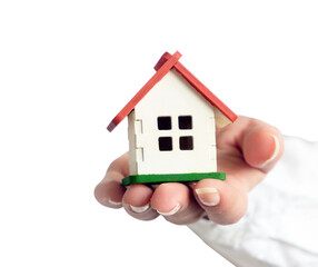 A female hand in a white shirt holding a small house