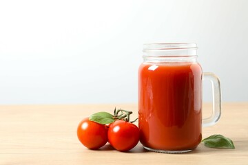 Tomato juice in a mason jar and fresh tomatoes on the table