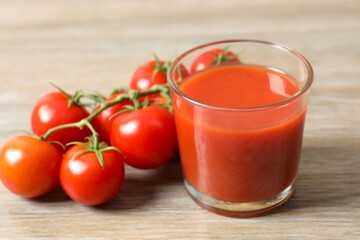 Tomato juice in a glass and fresh tomatoes on the table