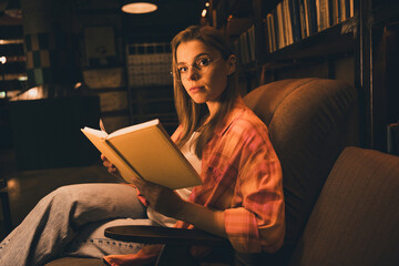 Photo of attractive young blonde woman reading book wear plaid shirt study comfortable dark library...