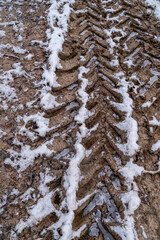 Tire tracks in the ice mud of winter in rural with snow. Off-road in frozen land. Landscape nature background.