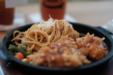 A delicious combination of crispy chicken and flavorful noodles served on a sizzling plate with vegetables