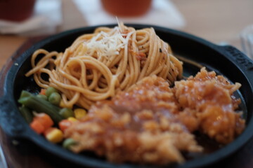 A delicious combination of crispy chicken and flavorful noodles served on a sizzling plate with vegetables