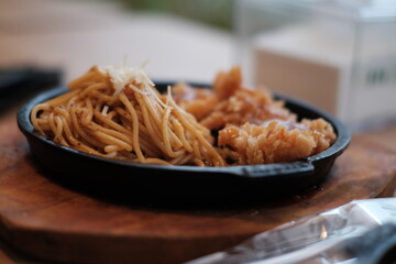 A delicious combination of crispy chicken and flavorful noodles served on a sizzling plate with vegetables
