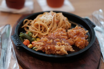A delicious combination of crispy chicken and flavorful noodles served on a sizzling plate with vegetables