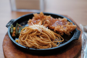 A delicious combination of crispy chicken and flavorful noodles served on a sizzling plate with vegetables
