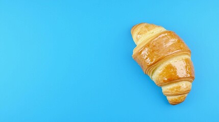 A Golden Croissant on a Vibrant Blue Background