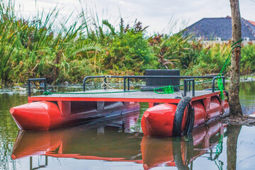 Multifunctional pontoon boat tied to a tree at a flood location, used to carry goods and also...