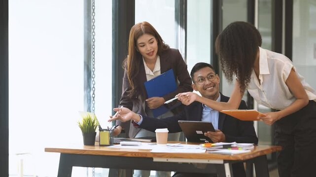 Collaborative Brainstorming:  A diverse team of professionals engages in a lively discussion, sharing ideas and insights around a laptop, fostering a dynamic and collaborative work environment.  