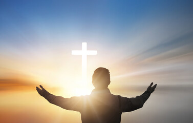 Silhouette of a man praying with a cross in the background