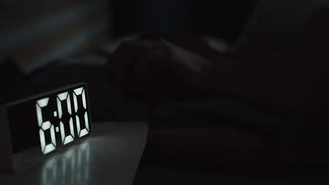 Man waking up at 6 a.m with digital alarm clock