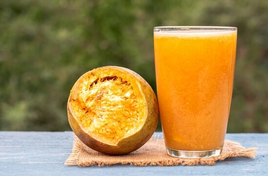 Closeup of Ripe Indian Bael Fruit Juice or Sarbat in a Glass or Wood Apple Isolated on Wooden Background with Copy Space, Also Known as Aegle Marmelos, Bengal Quince, Japanese Bitter Orange or St