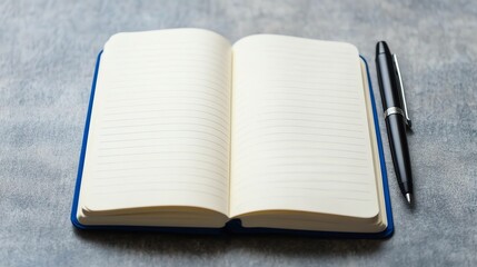 An open notebook with lined pages, next to a black pen, is on a grey surface.