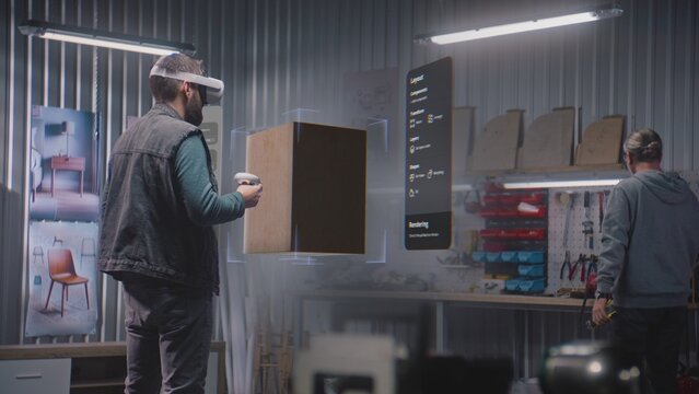 Modern workshop: Designer or artisan wearing augmented reality headset assembles coffee table in virtual space using app with AI user interface. 3D graphics of holographic furniture. VFX animation.