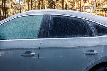 Side view of a frozen car covered with frost and ice on freezing weather.