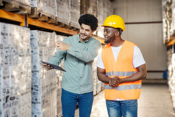 Young diverse storage manager with tablet talking to his migrant black worker at warehouse.