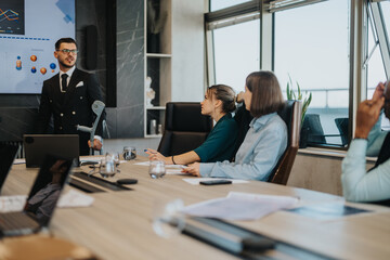 Fototapeta premium A multicultural group of people attending a business presentation in a modern office setting, showcasing teamwork and collaboration. The atmosphere is focused, with visual aids displayed on a screen.