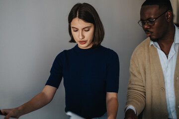 Multicultural business workers analyzing and discussing a project together. The diverse business employees collaborate, brainstorming strategies to enhance their project outcomes in an office setting.