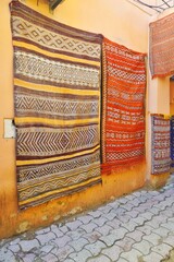 Vintage rugs with colorful intricate woven patterns for sale at an outdoor marketplace in Morocco