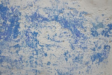 Abstract blue and white background pattern with scratched and chipped blue paint over chalky white wall