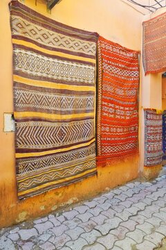 Vintage rugs with colorful intricate woven patterns for sale at an outdoor marketplace in Morocco