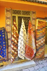 Colorful vintage handwoven rugs for sale outside a Moroccan market stall