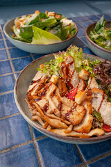 Grilled mushrooms and chicken breast salad on blue tiled surface