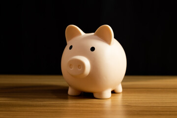 Piggy bank on wood with black background, concept of economy and savings © Answer 7